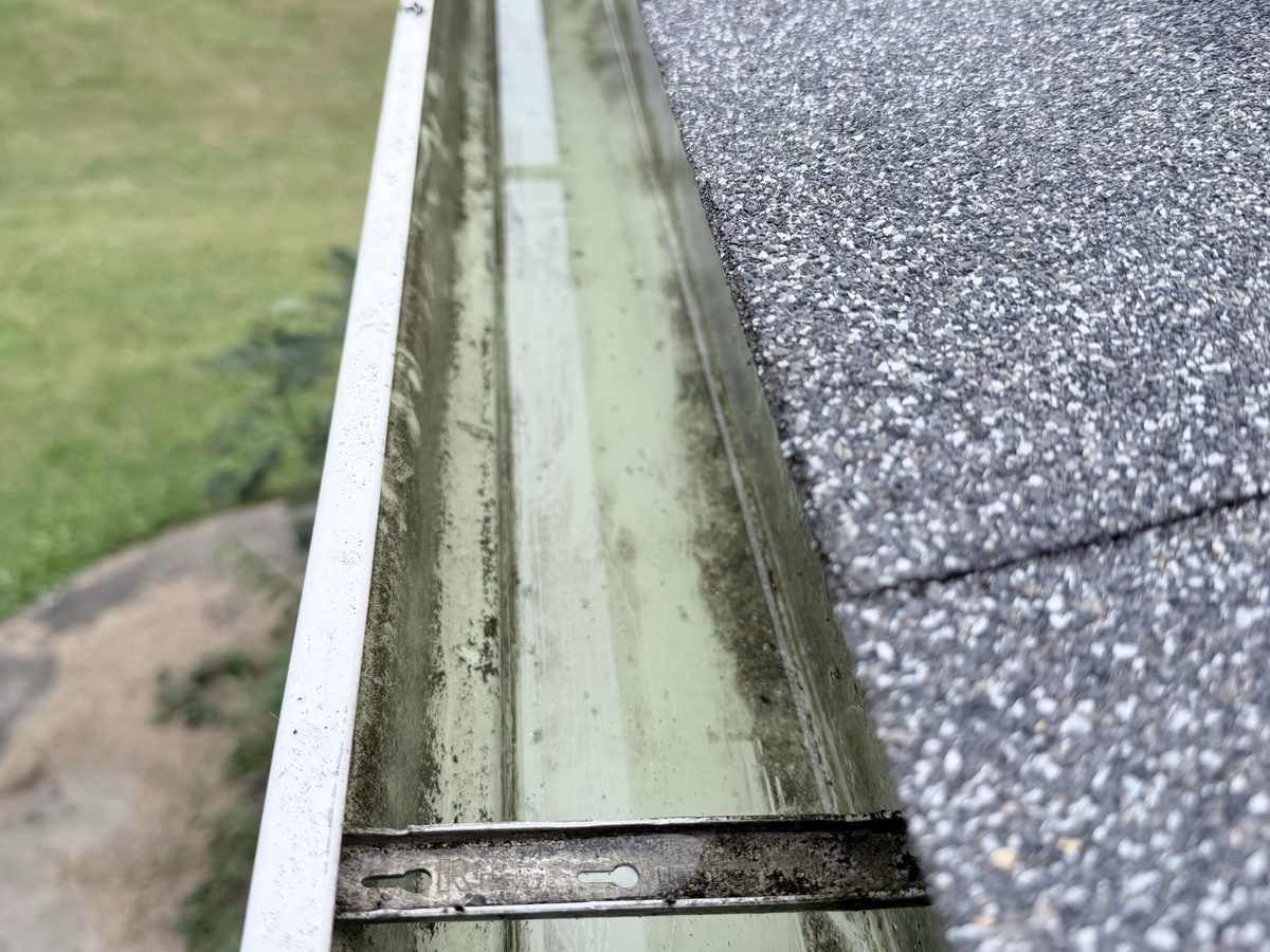 The gutter after cleaning, with rinse water running toward the downspout