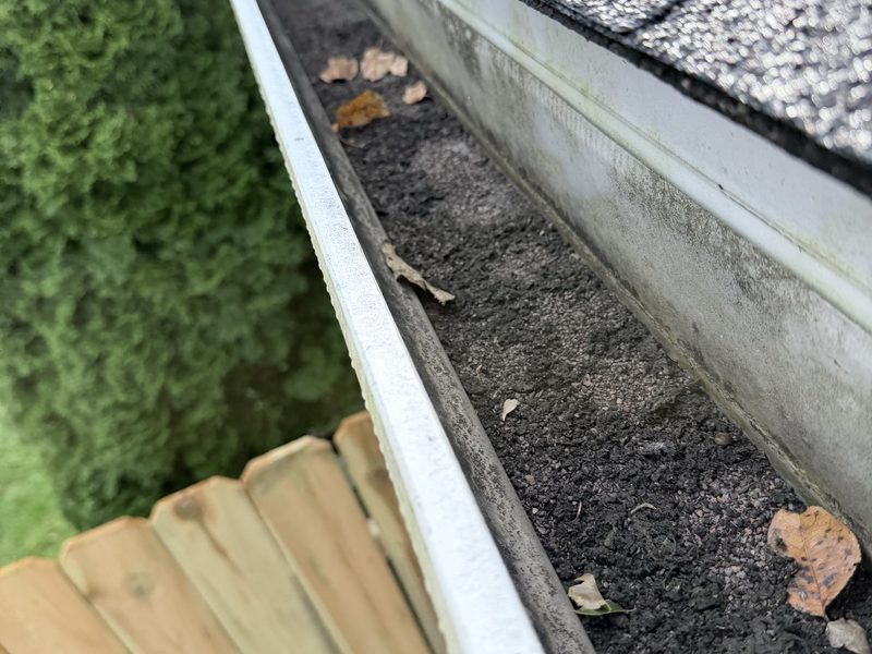 Gutter packed with shingle grit and leaves before a Guttrz cleaning