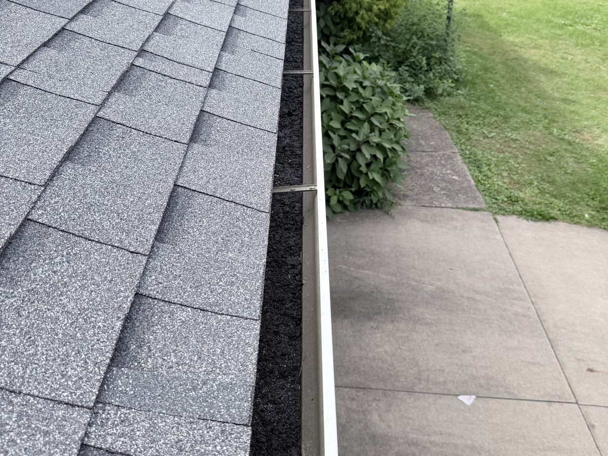Gutter run full of dark debris before a Guttrz cleaning