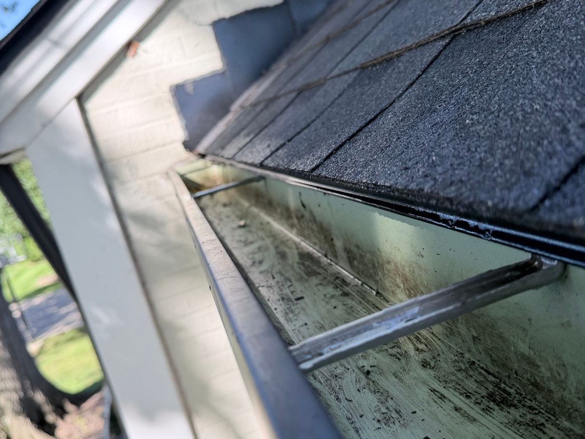 A long gutter run cleaned to the far end, with the hangers and gutter floor showing