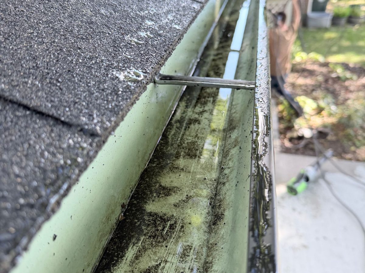 The same back gutter cleaned out and wet from flushing, with the downspout outlet open