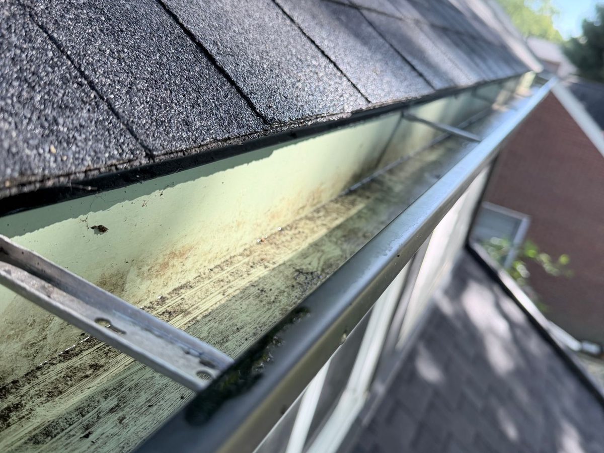 The same gutter corner below a gable end, empty after a hand cleanout