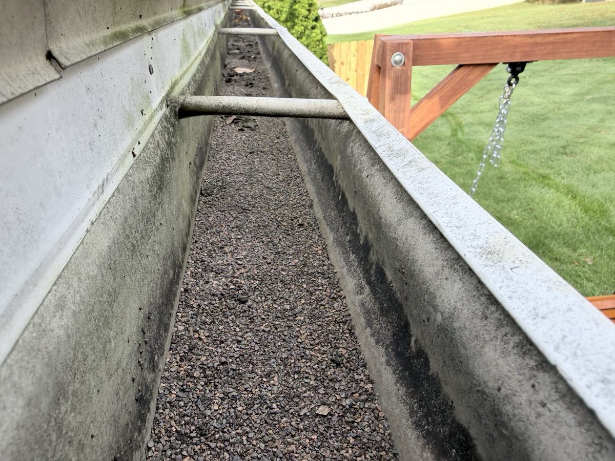 Close-up of a gutter filled with dark shingle grit