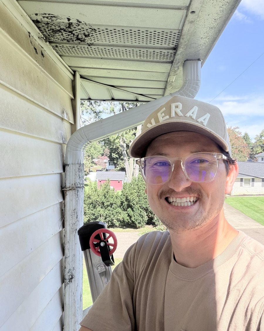 Christian Schaffner, owner of Guttrz, smiling beside a downspout on a job
